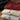 Folded shirts in red, beige, and gray on a wooden surface