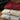 Folded shirts in red, beige, and gray on a wooden surface