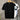 Black t-shirt with white stripes on sleeves hanging on a rack against a gray wall.